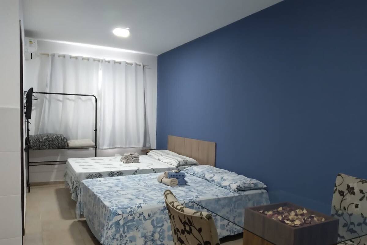 Quarto de dormitório com duas camas, uma cama beliche, uma escrivaninha e uma cadeira.