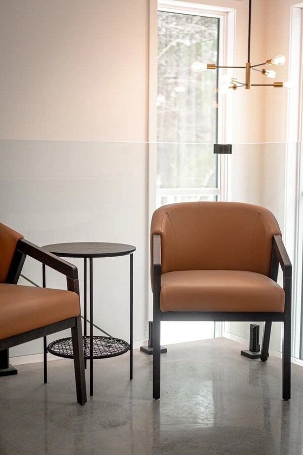 Une pièce moderne avec un fauteuil en cuir marron, une petite table ronde et un luminaire suspendu.