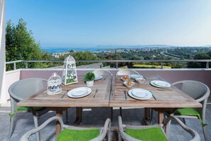 A wooden table set for two with wicker chairs, a birdcage, and a small potted plant. - Villa Stefania (Chania)