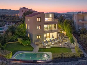A modern two-story building with a pool and outdoor seating area.
