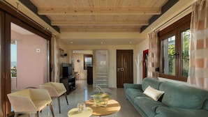 A modern living room with a green sofa, two chairs, a coffee table, and a TV. - Villa Stefania (Chania)