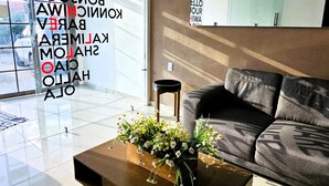 Een moderne woonkamer met een bank, een bijzettafeltje met bloemen en een groot raam met uitzicht.