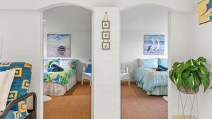 Una habitación con dos camas, una planta grande en maceta y decoración náutica.
