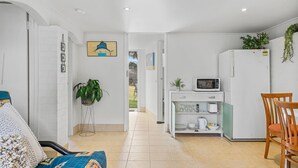 Cocina compacta con microondas, refrigerador y comedor con una silla.