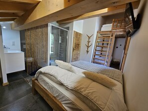 Ein Schlafzimmer mit einem hölzernen Bett, ein Badezimmer mit einem weißen Waschbecken und einer Holzleiter.
