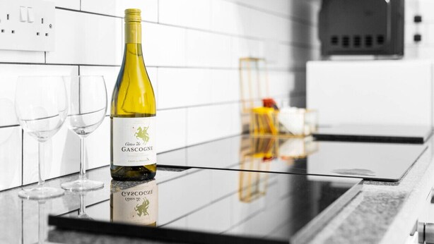 Una cocina con una botella de vino, dos copas y un microondas.