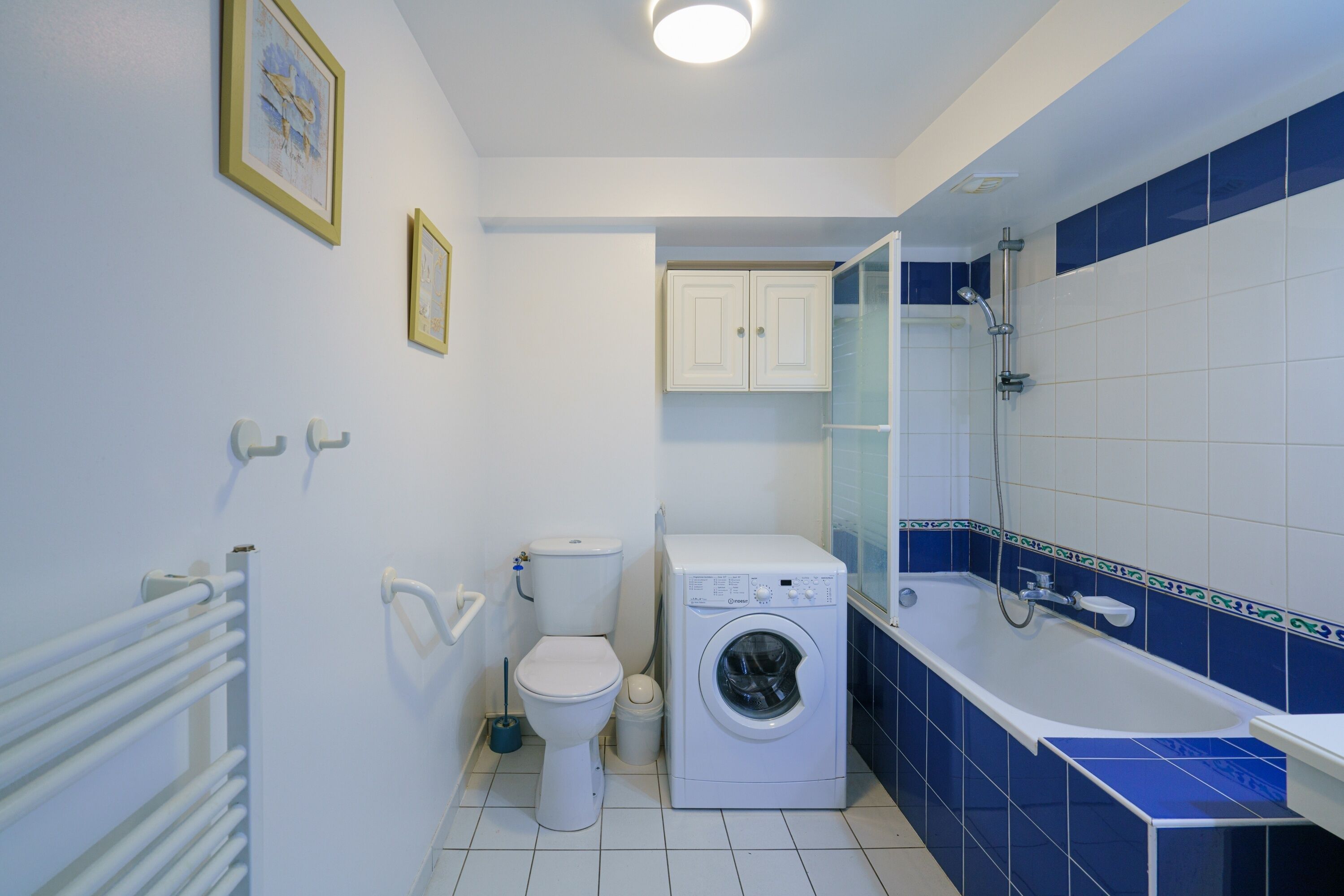 Une salle de bain équipée d’un lave-linge, de toilettes et d’une baignoire.
