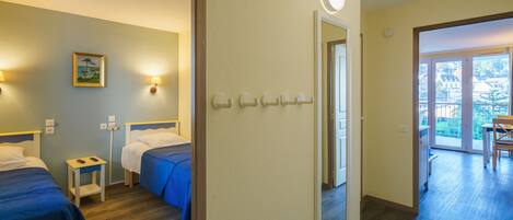 Et hotelværelse med to senge, et lille natbord, et spejl og en dør til en balkon.