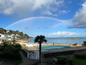 Une vue sur la côte, avec un arc-en-ciel, des maisons et une piscine.