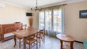 Un coin repas avec une table et des chaises en bois, un buffet en bois, un lustre et une fenêtre avec des rideaux.