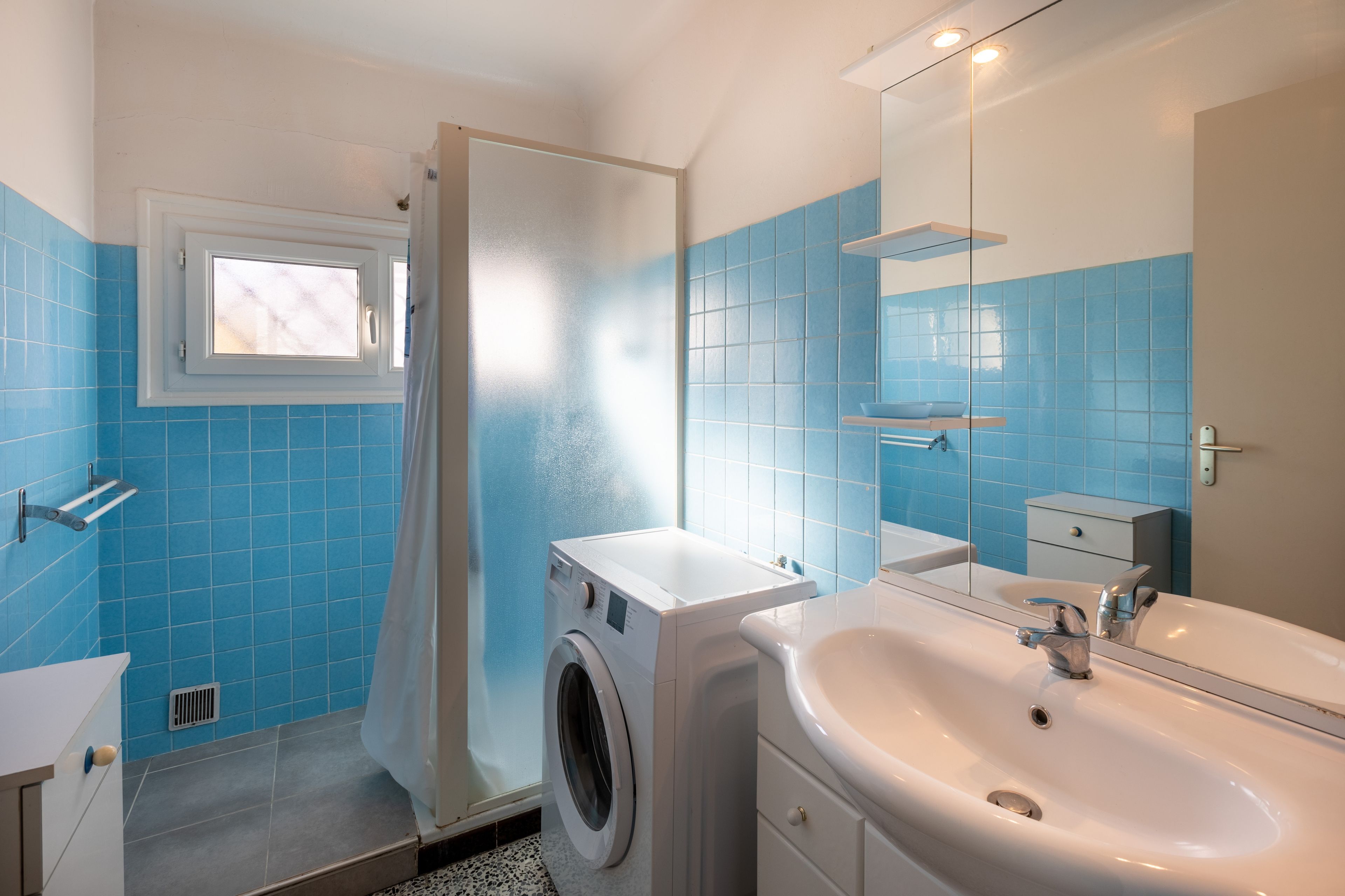 Un baño moderno con lavadora, lavabo y espejo.