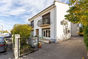 A two-story building with a balcony, a gated entrance, and a parked car. - Pamplemousse - Appt à 10min d'Argelès-Sur-Mer (Saint-André)