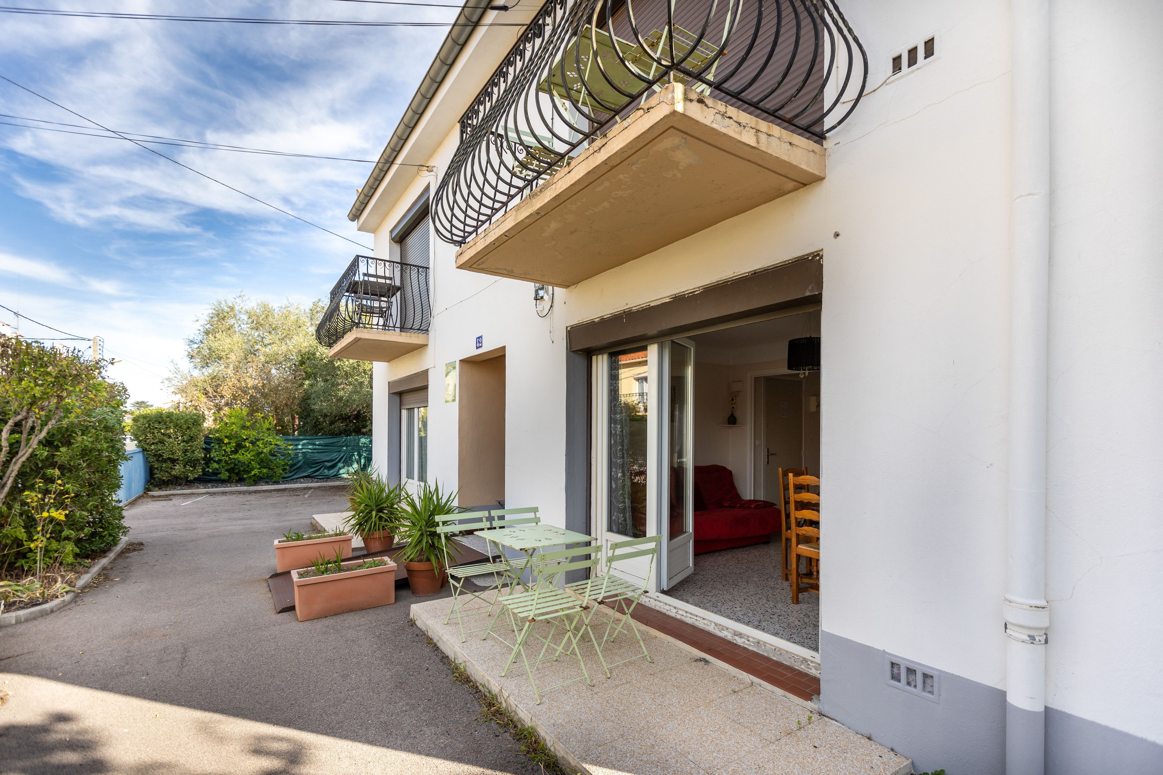 A residential building with a balcony, outdoor seating, and a red sofa inside.