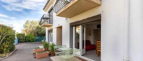 A residential building with a balcony, outdoor seating, and a red sofa inside.