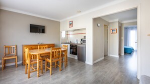 Eine moderne Küche mit Essbereich, Holzmöbeln und einem Flachbildfernseher.