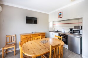 A compact kitchen with a dining table, chairs, a microwave, a coffee maker, and a TV mounted on the wall. - Mandarine - Appt à 10min d'Argelès-Sur-Mer (Saint-André)