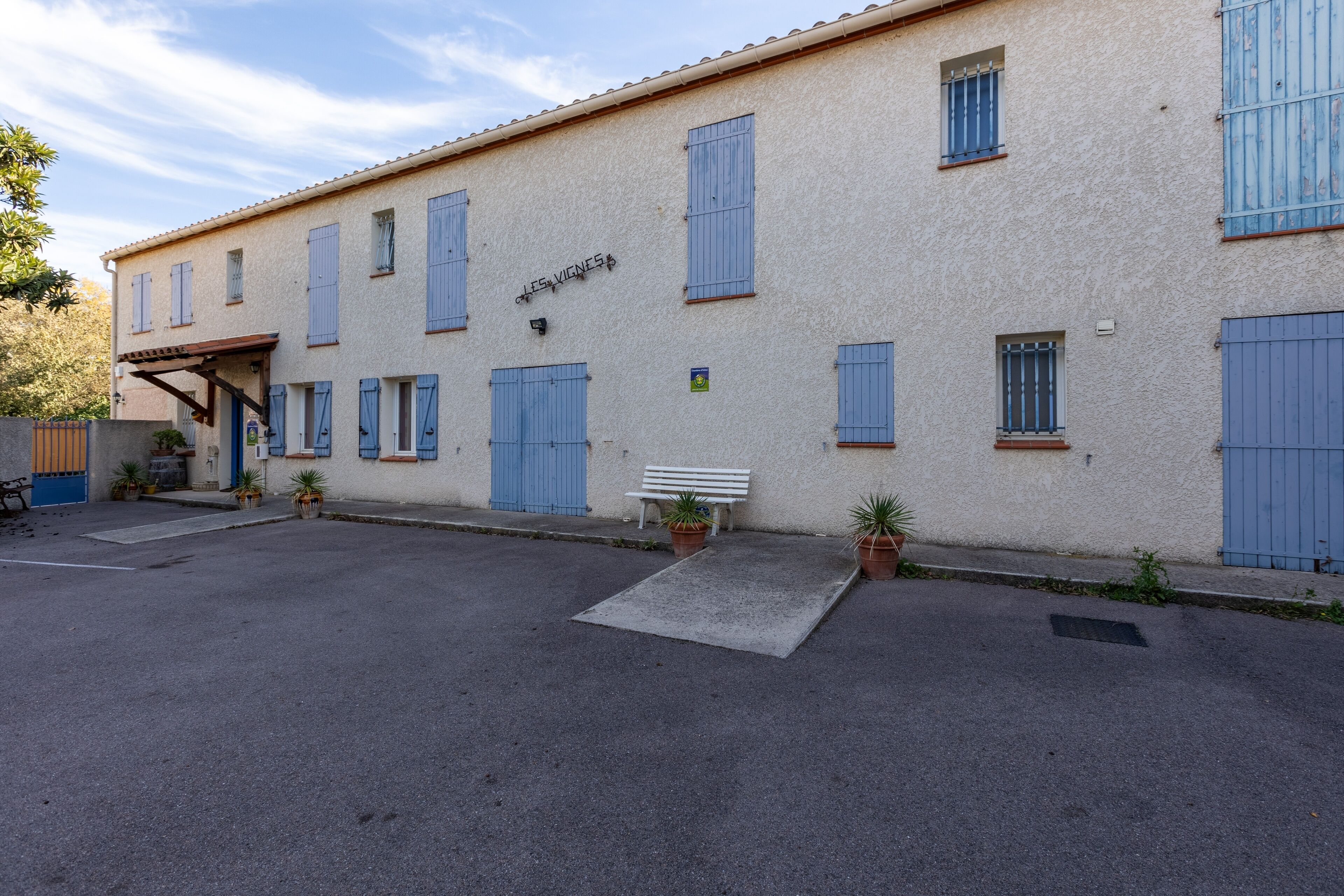 A building with a sign reading "LES VINES" and a white bench outside.