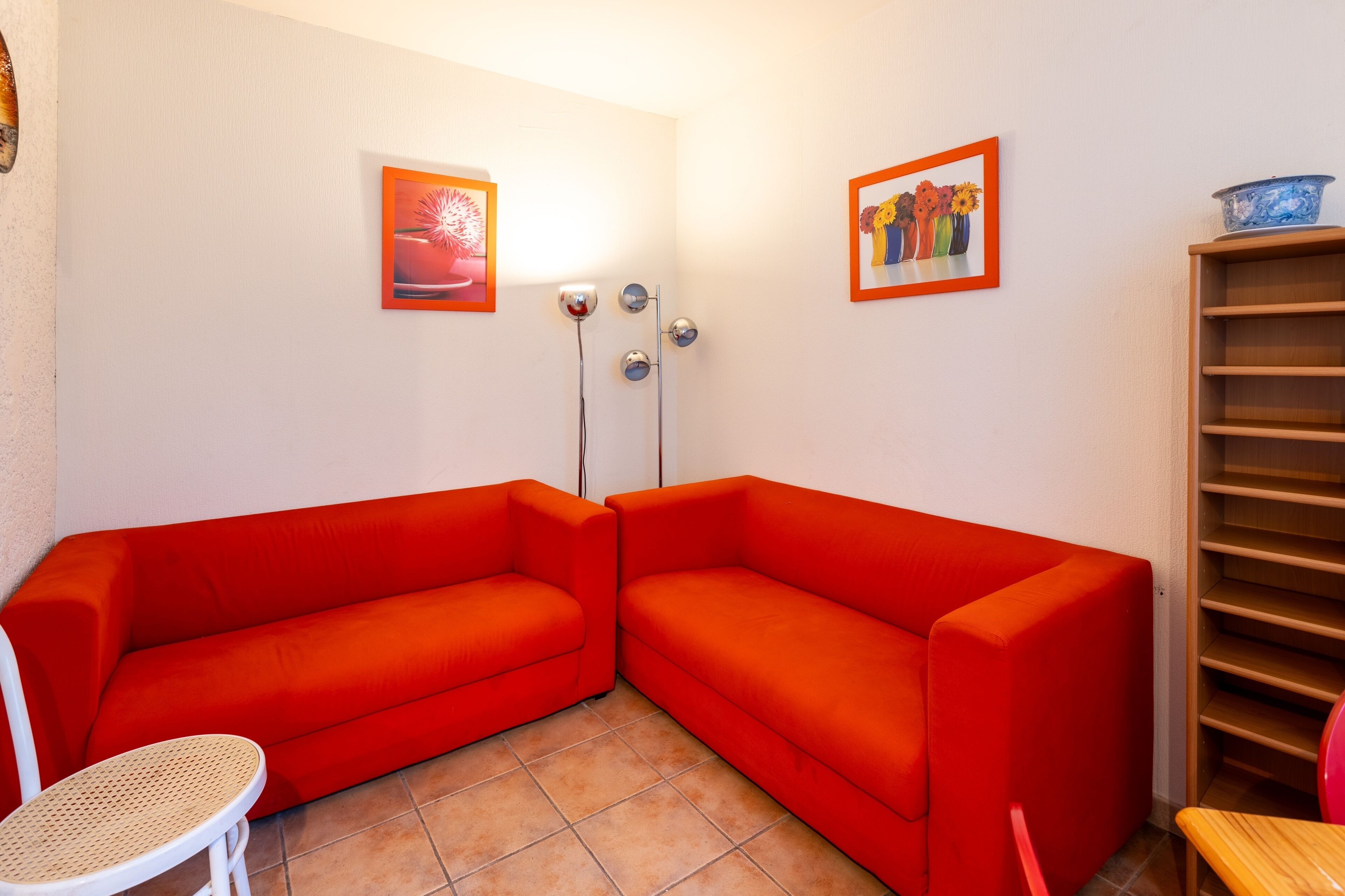 A room with two red sofas, a small round table, and two wall-mounted light fixtures.