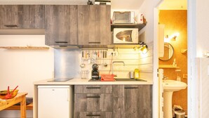 Eine kleine Küche mit Holzausstattung, einer Mikrowelle, einem Spülbecken und einem kleinen Kühlschrank.