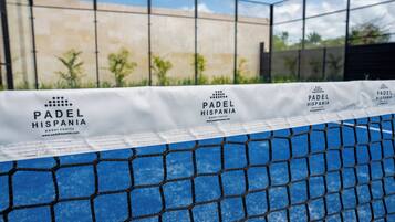 A tennis court with a net and a banner displaying 'PADEL HISPANIA' branding.