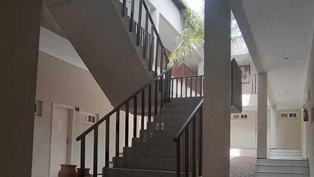 Un intérieur spacieux avec un escalier central, des sols carrelés et un banc.