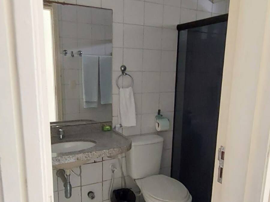 Un baño pequeño con azulejos blancos, un inodoro, un lavabo y un espejo.