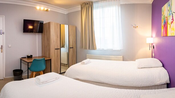 A hotel room with two beds, a desk, a chair, a TV, and a window with curtains. - résidence helios (Villeneuve-Saint-Georges)