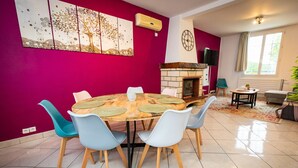 A dining area with a round table, six chairs, a fireplace, and a large abstract painting on the wall. - résidence helios (Villeneuve-Saint-Georges)