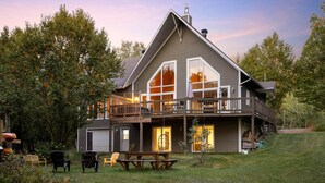 A two-story house with a balcony, a covered patio, and a large window. - Hôtel à la maison - Beaufranc chalet (Inverness)