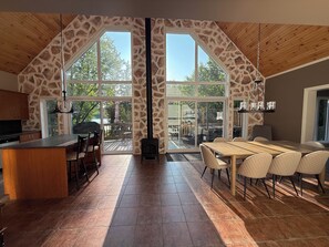 Una cocina amplia con detalles en piedra, ventanas grandes, una isla central y un área de comedor con sillas.