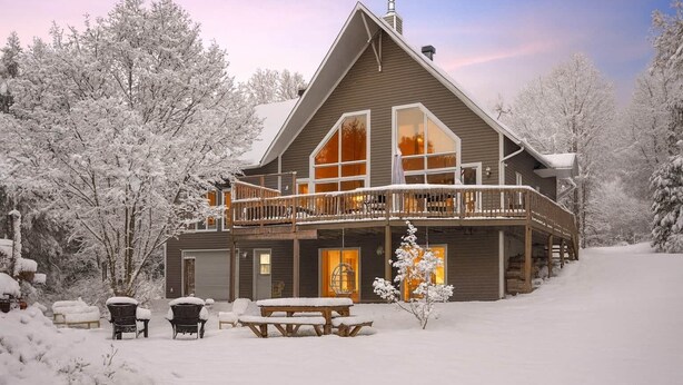 A large, two-story lodge with a balcony and a covered porch, surrounded by snow-covered trees. - Hôtel à la maison - Beaufranc chalet (Inverness)