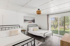 Un dormitorio moderno con dos camas, un ventanal grande y vistas al exterior.