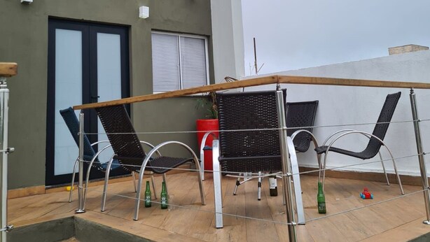 A rooftop terrace with a table and chairs, a railing, and a view of the building's exterior. - Casa de Alto Padrão Condomínio Privado (Chapada dos Guimarães)