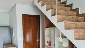 A modern interior with a wooden staircase, a wooden door, and a white cabinet with drawers. - Casa de Alto Padrão Condomínio Privado (Chapada dos Guimarães)