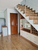 Un interior moderno con una escalera de madera, una puerta de madera y un armario blanco con cajones.