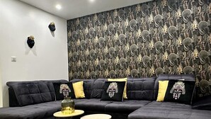 A modern living room with a sectional sofa, two round tables, and a decorative wall with a leaf pattern. - Res. Marie Galante Lac du Der (Moncetz-l'Abbaye)