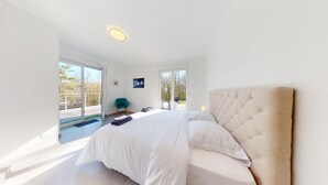 Un dormitorio moderno con una cama grande, una silla y un balcón con vistas.