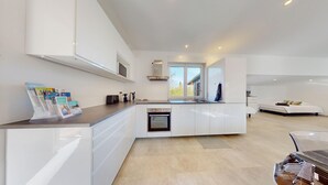 Una cocina moderna con armarios blancos, horno empotrado y ventana que proporciona luz natural.