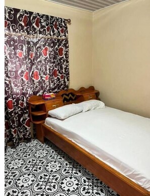 Cozy retreat with a single bed, wooden headboard, and a patterned floor.