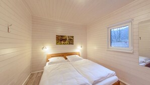 A cozy room with a wooden bed, a window with a view of trees, and a painting on the wall.