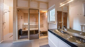 A modern bathroom with a wooden interior, a glass shower enclosure, and a large mirror.