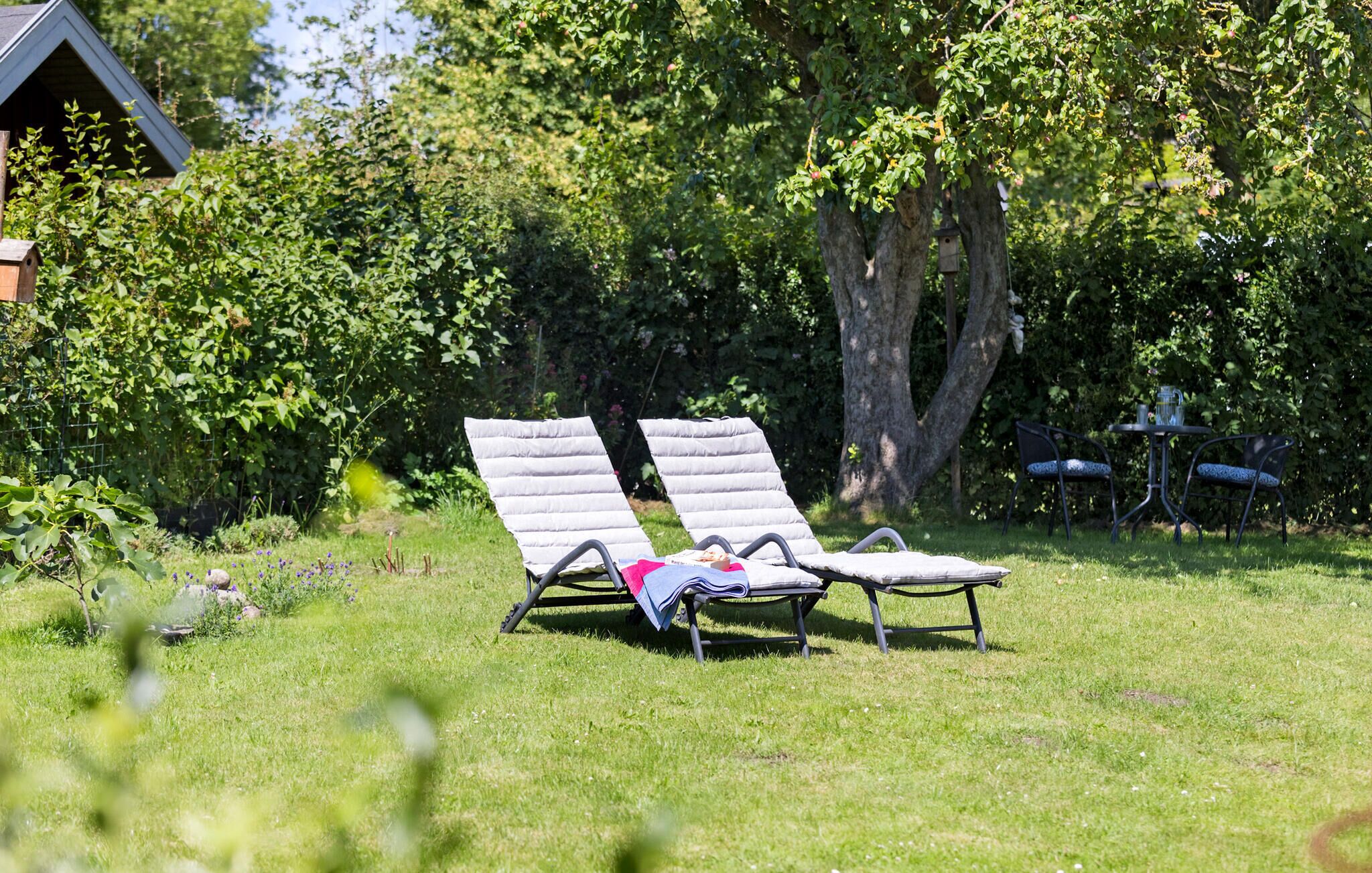 Een gazon met een zithoek, een klein tafeltje en een vogelvoerder.