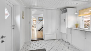 Une cuisine moderne avec des meubles blancs, un réfrigérateur encastré et une fenêtre ornée d’un rideau jaune.