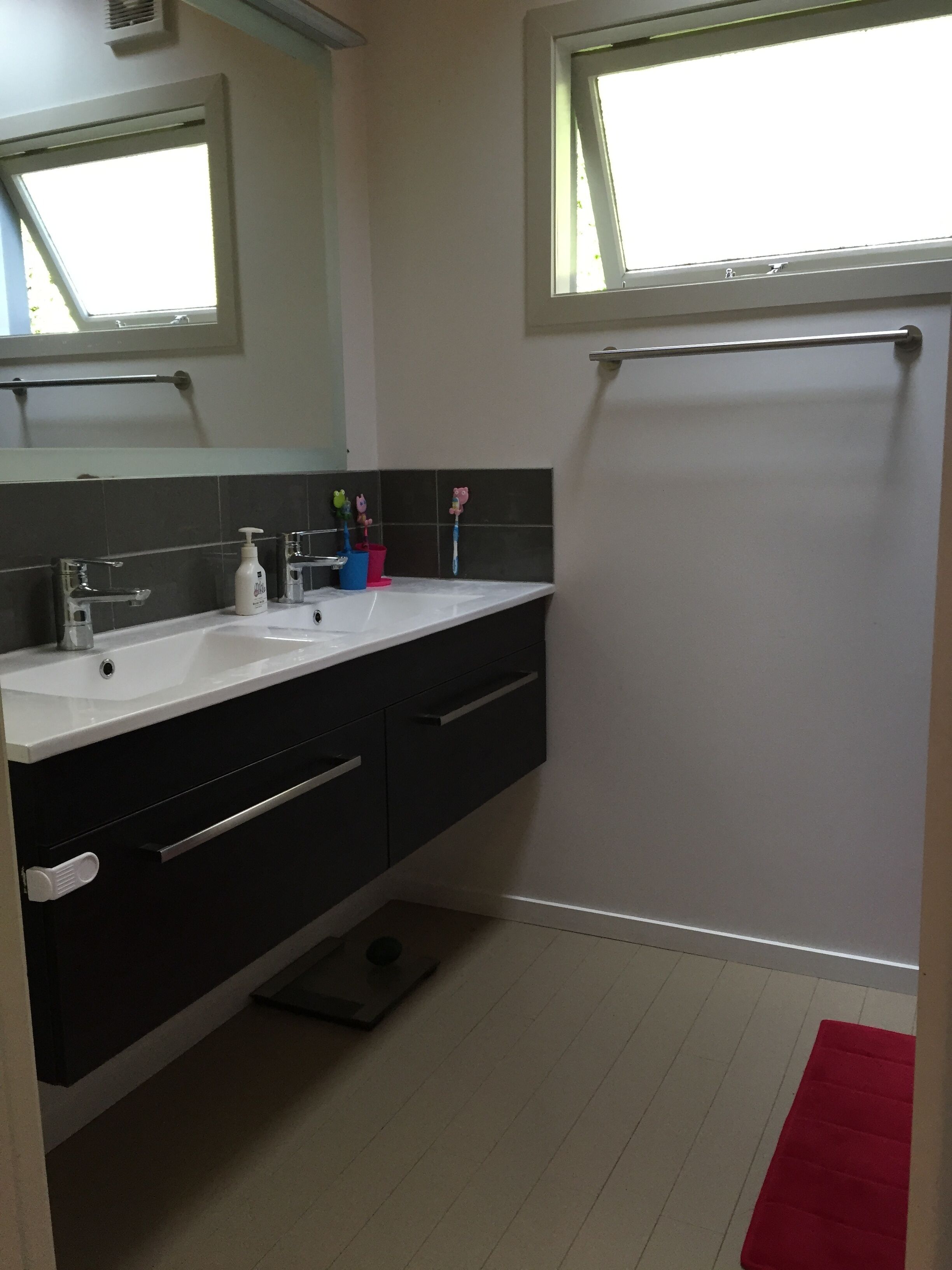 A bathroom with a white sink, black vanity, and a red bath mat.