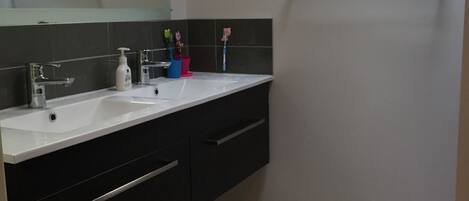 A bathroom with a white sink, black vanity, and a red bath mat.
