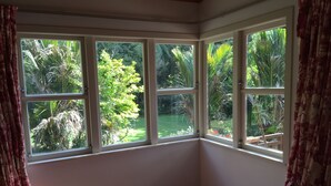 Une chambre d’angle avec une baie vitrée donnant sur un jardin.