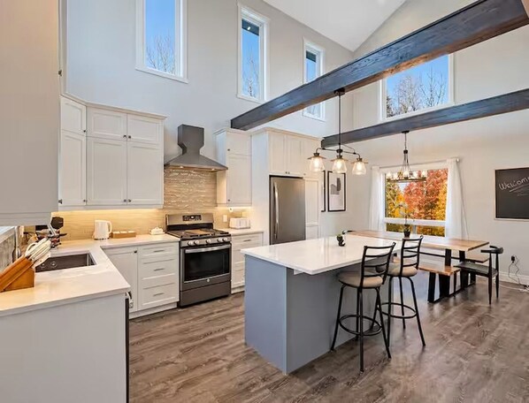 A spacious kitchen with a large island, built-in appliances, and a high ceiling with exposed beams.