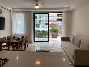 Ein modernes Wohnzimmer mit Essbereich, einer Couch und einem Balkon mit Blick auf Gebäude und Grünflächen.