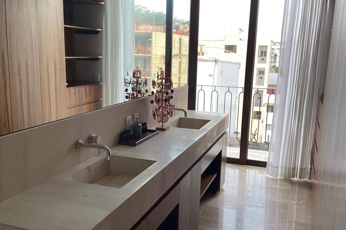 Un bany modern amb un lavabo gran, mobles de fusta i vista a l'exterior a través d'una porta de vidre.