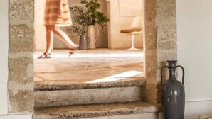 A stone archway leading to a room with a fireplace, a potted plant, and a vase on a table. - Masseria Angiulli Piccolo w pool / Salento Apulia (Grottaglie)